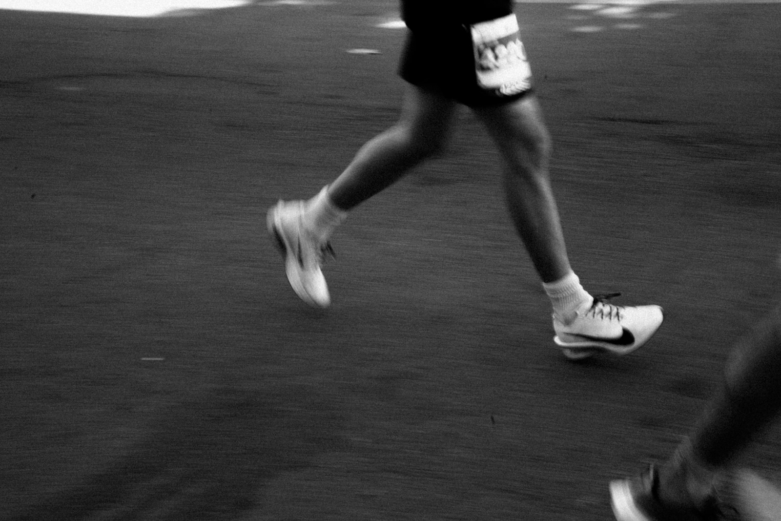 Runner mid-stride wearing sneakers with a race bib